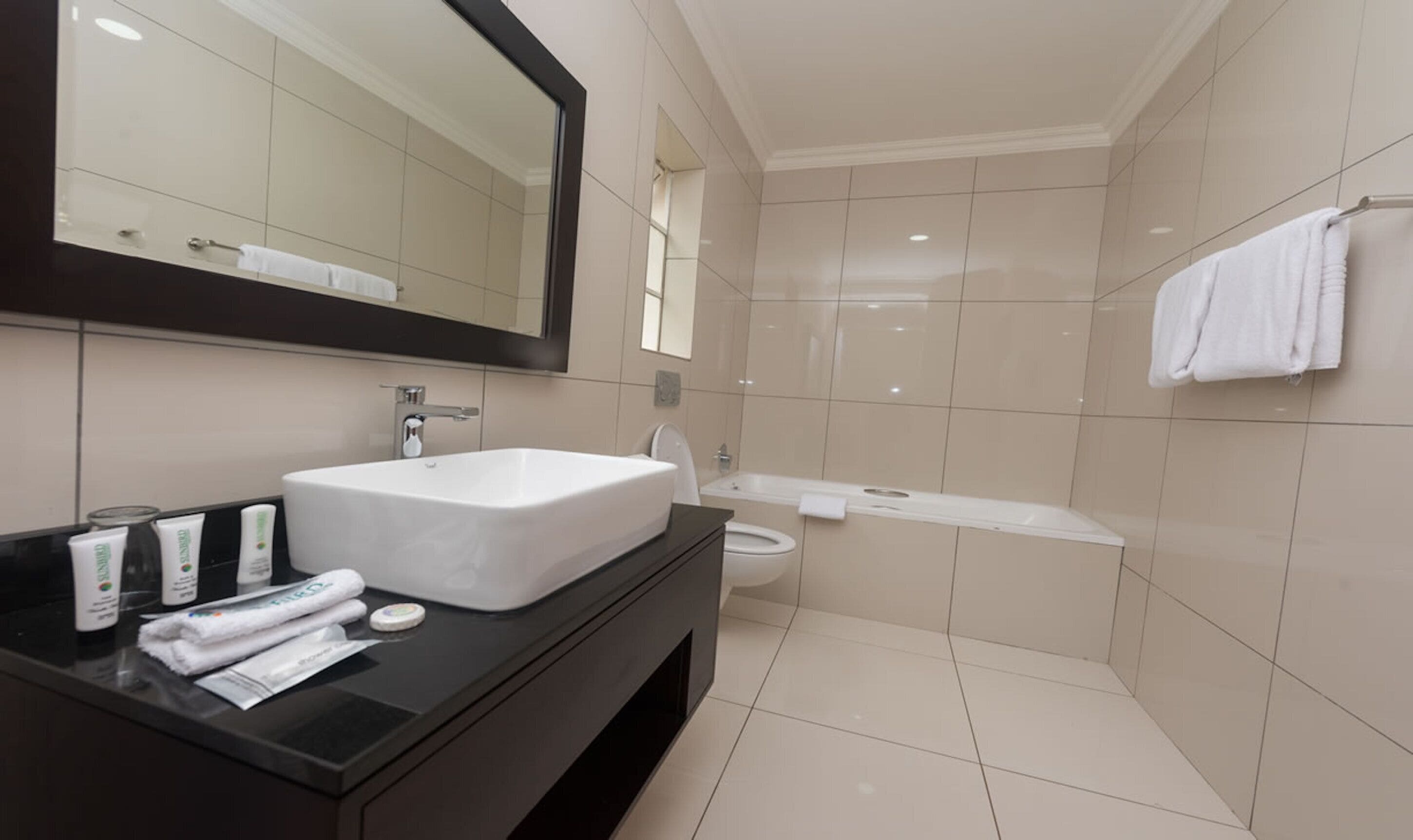A modern bathroom with a large rectangular sink, a toilet, and a bathtub.