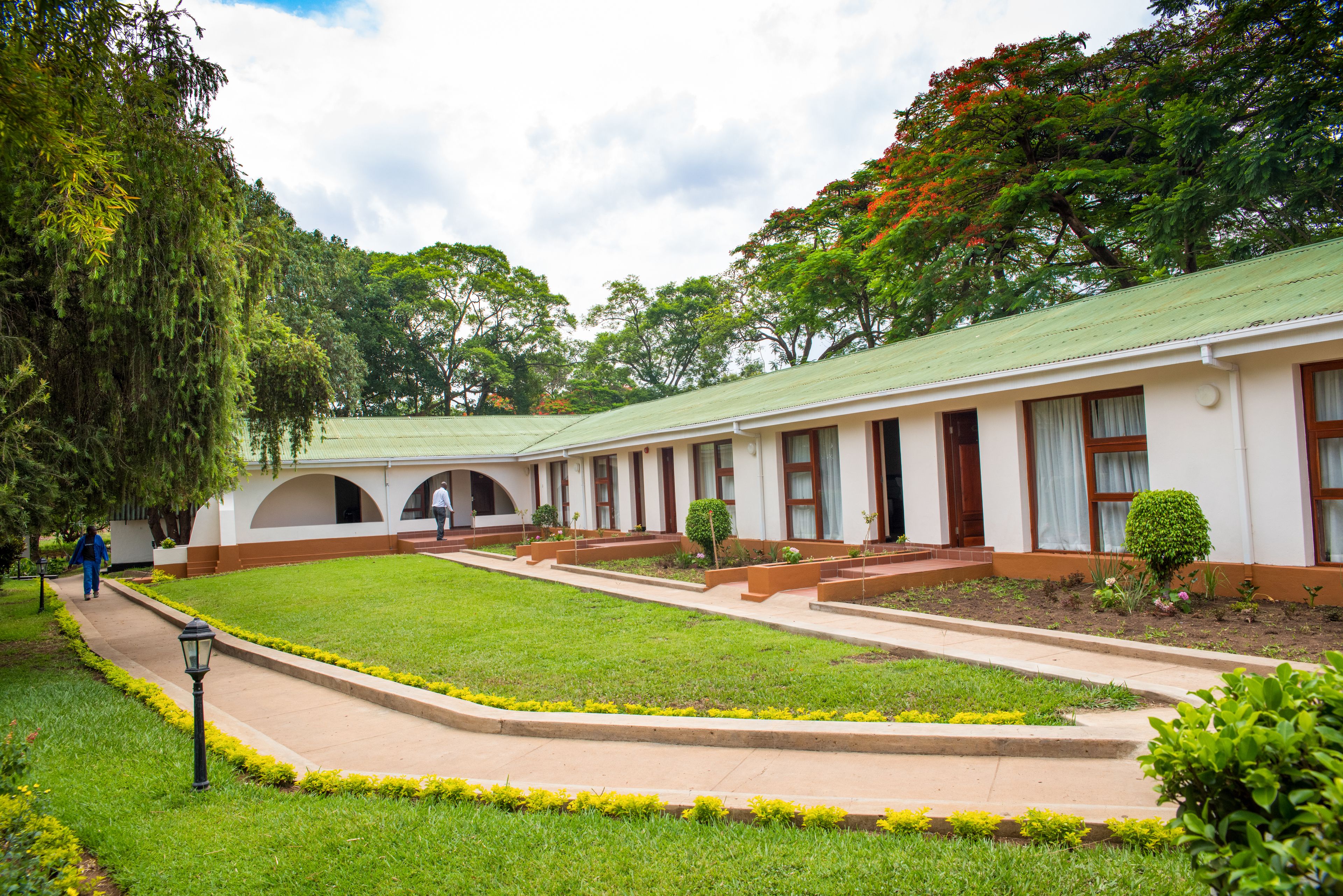 A building with a green roof, white walls, and a central courtyard with a pathway.