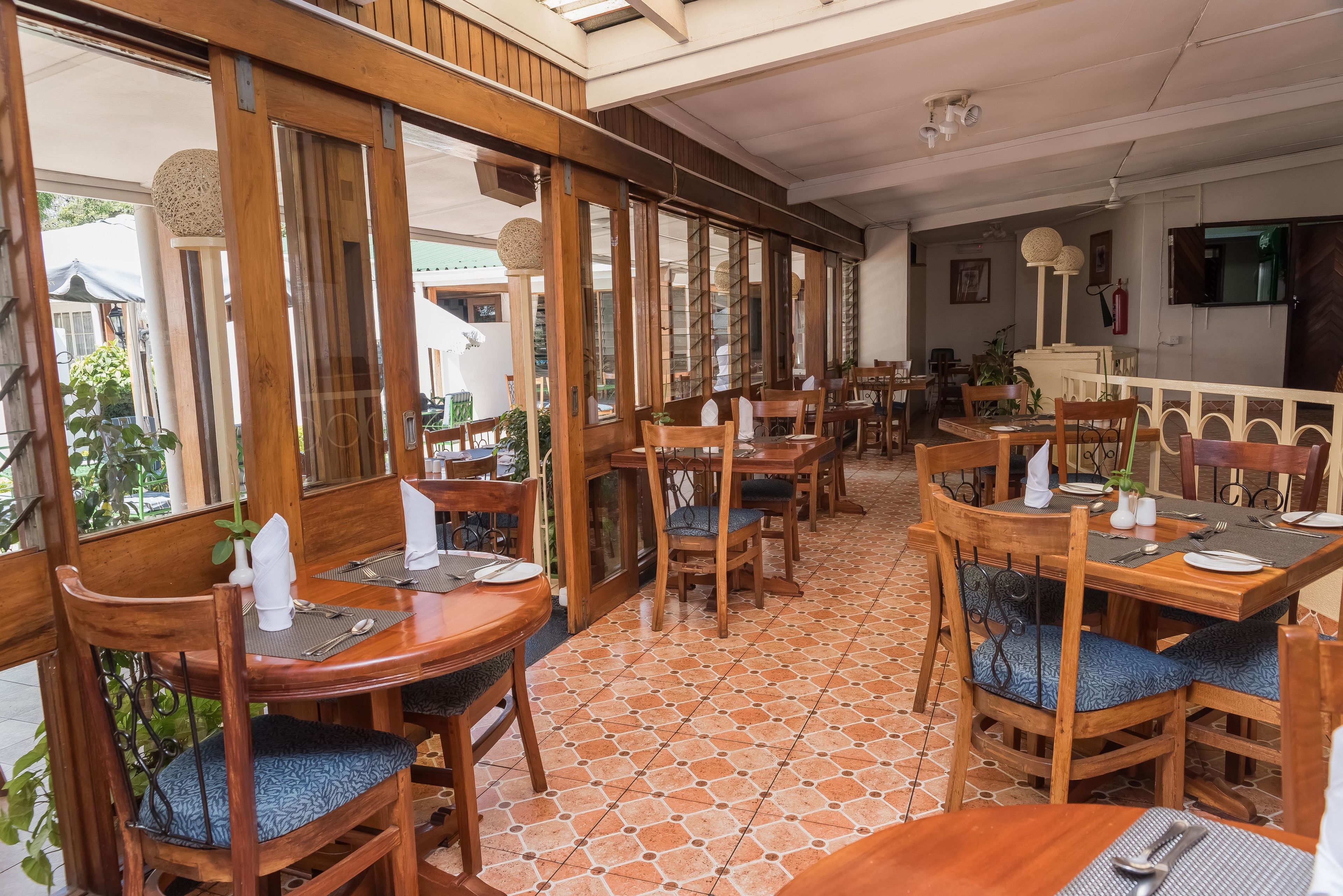 Un restaurante con mobiliario de madera, suelo de baldosas y ventanas grandes.