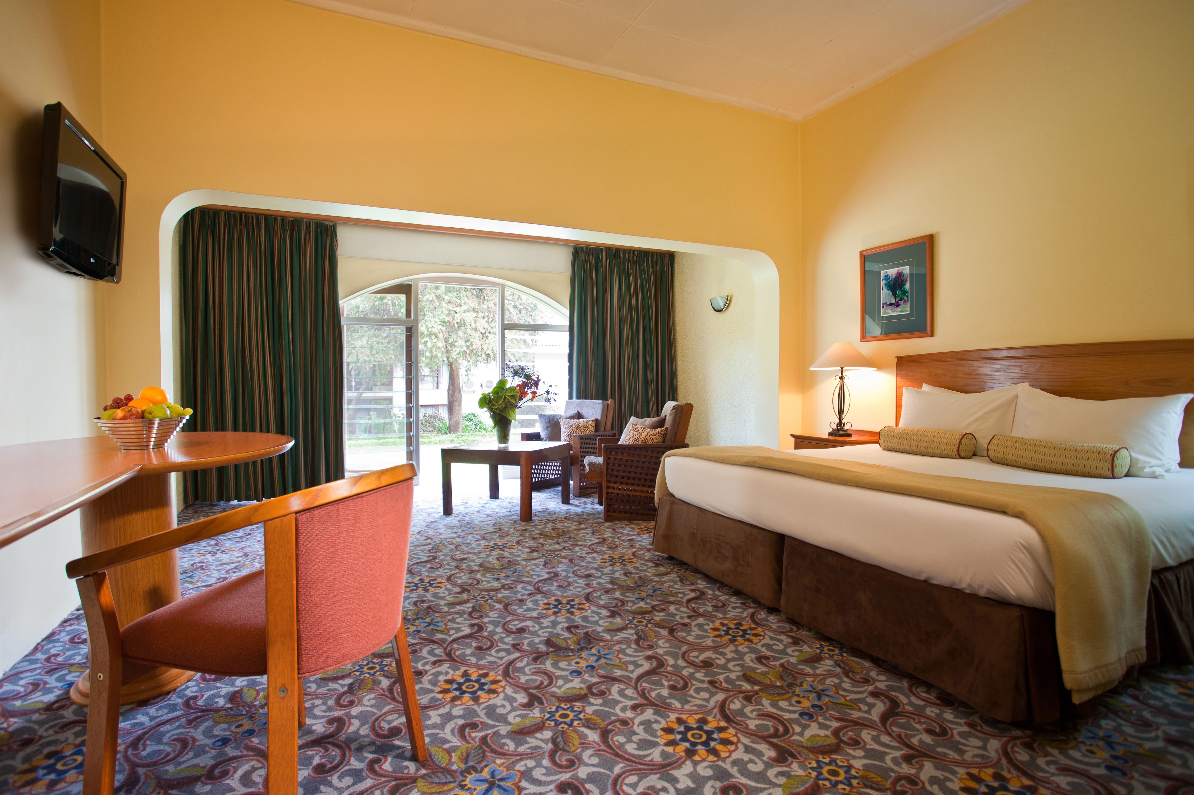 Una habitación de hotel con cama, escritorio, silla, mesa y televisor.