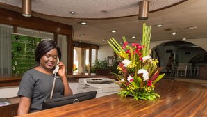 A reception desk with a telephone, a printer, and a floral arrangement. - Sunbird Lilongwe (Lilongwe)