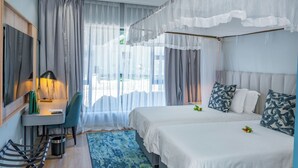 Habitación de hotel con cama, escritorio, silla, cubo de basura y ventana con cortinas.
