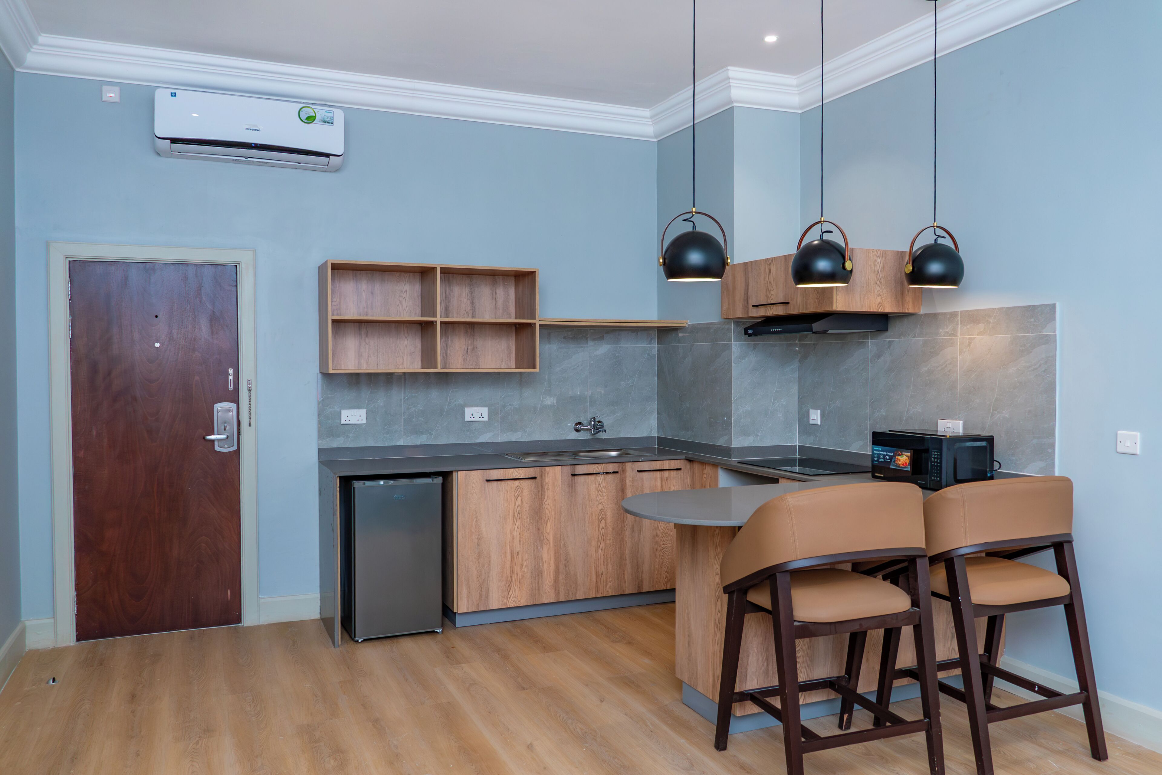 Una cucina moderna con isola integrata, mobili in legno, un forno a microonde e illuminazione a sospensione.