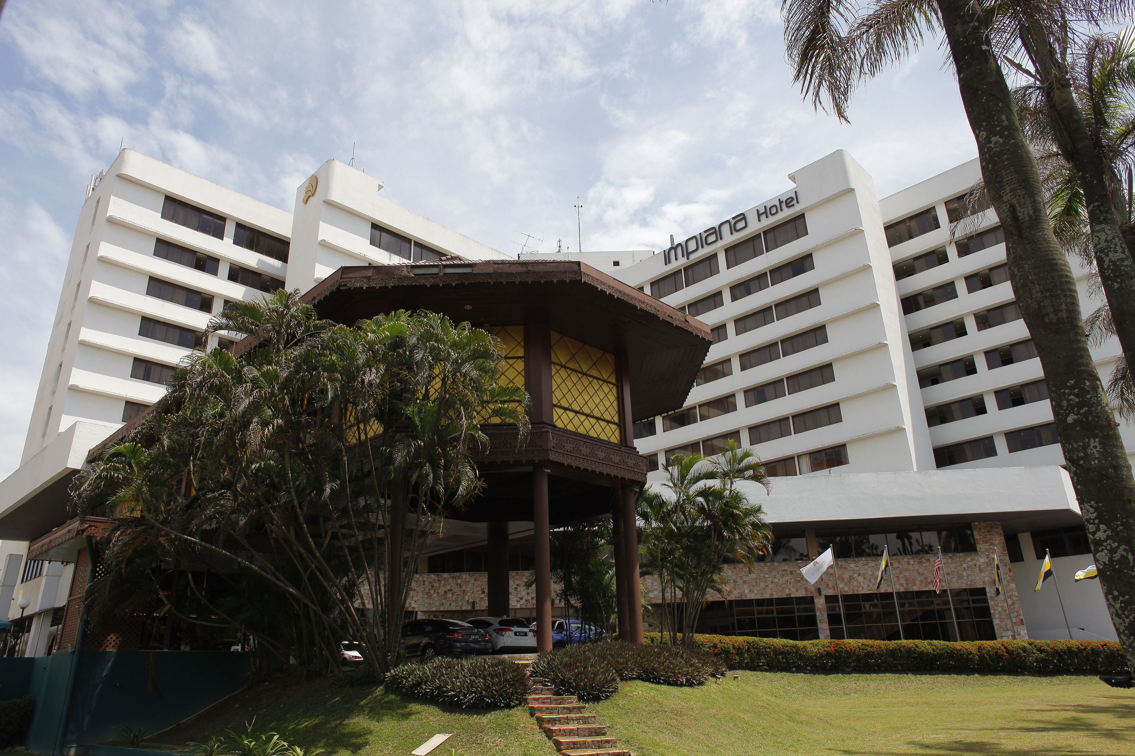 A hotel with a modern design, featuring multiple floors and a covered entrance area with palm trees.