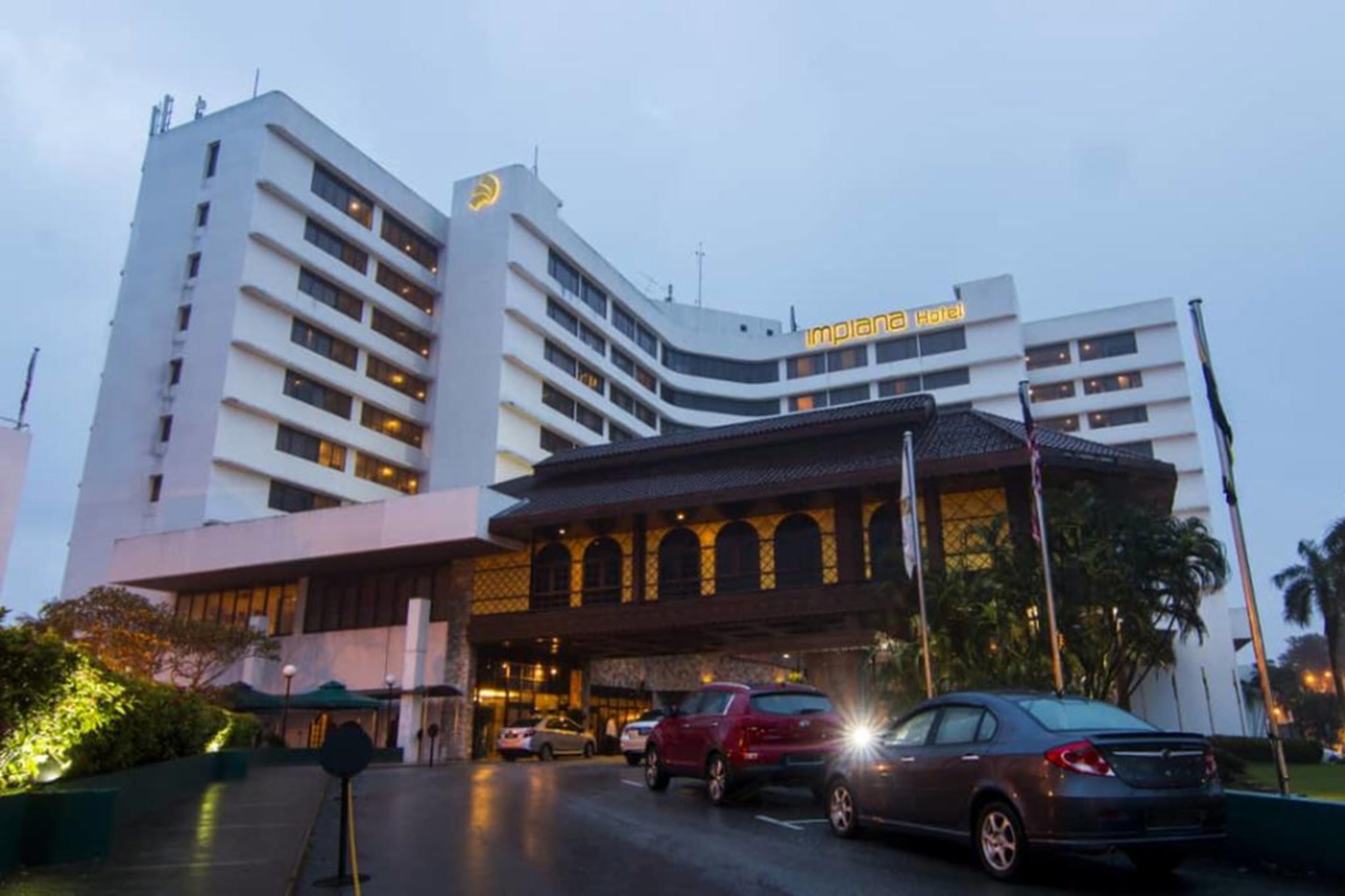 A multi-story hotel with a prominent entrance and several parked cars.