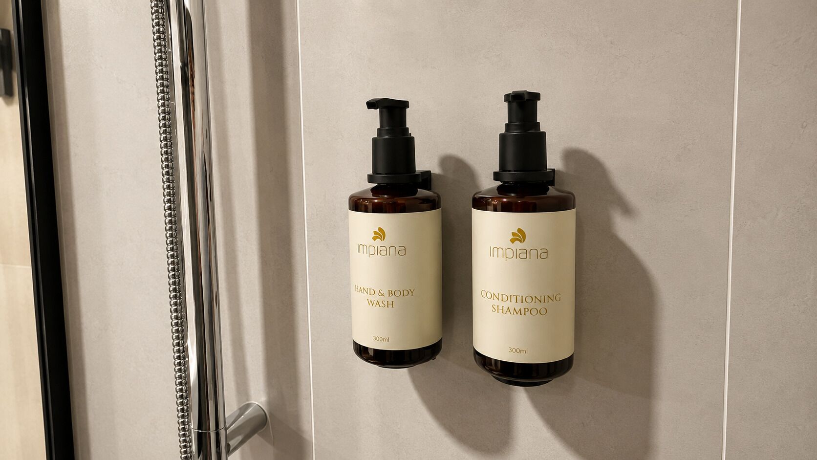 Two bottles of Implana hand and body wash and conditioning shampoo mounted on a wall.