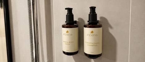 Two bottles of Implana hand and body wash and conditioning shampoo mounted on a wall.