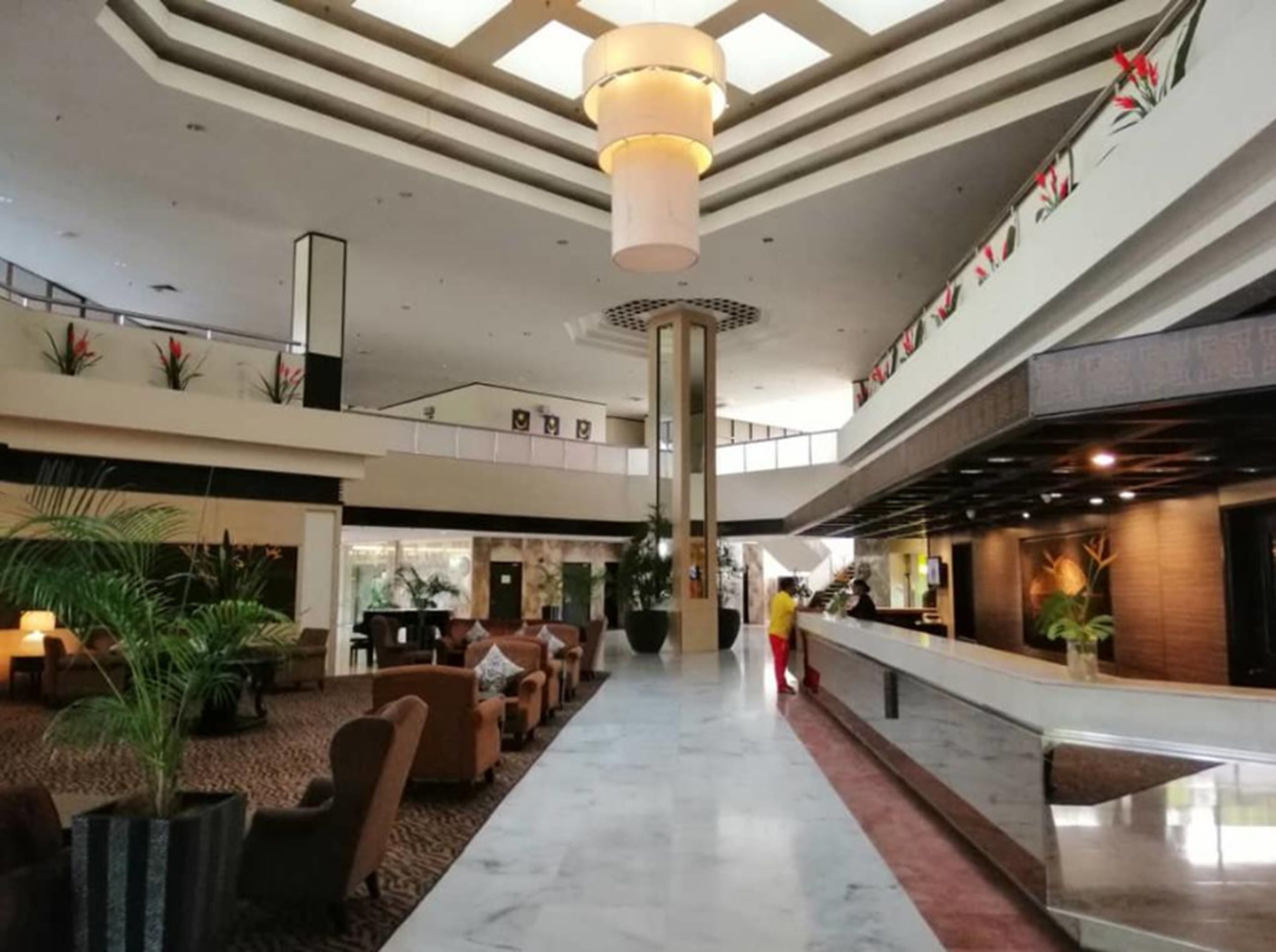 A spacious lobby with a high ceiling, a central column, and a reception desk on the right.