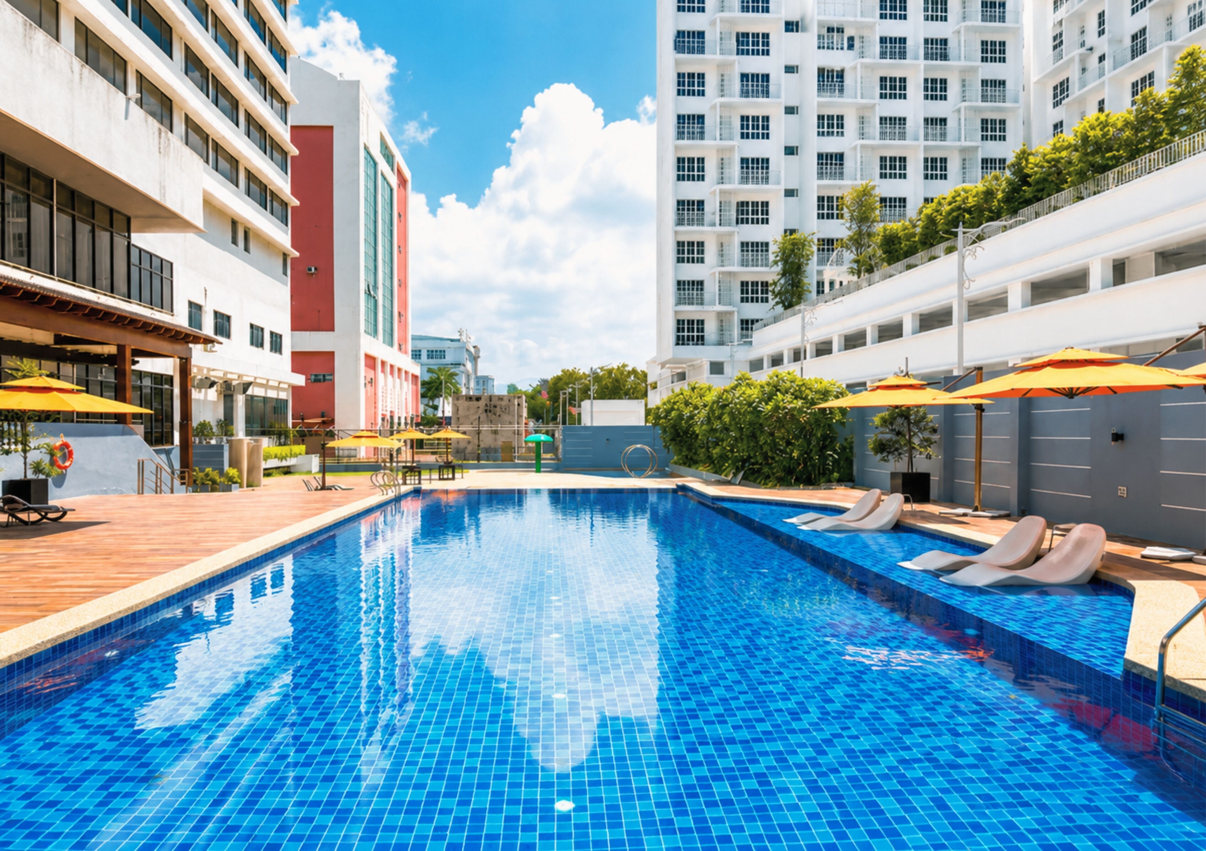 A swimming pool with tiled flooring, lounge chairs, and umbrellas.