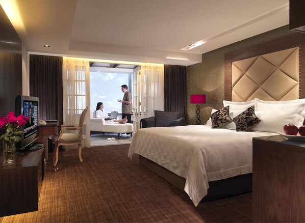 A hotel room with a large bed, a desk with a computer, a TV, and a view of the sky through the window. - Conrad Kuala Lumpur (Kuala Lumpur)