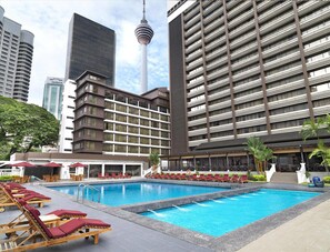 A hotel with a swimming pool, lounge chairs, and a view of nearby buildings. - Conrad Kuala Lumpur (Kuala Lumpur)