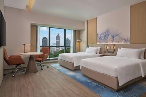 A hotel room with two beds, a desk, a chair, a large window with a city view, and a wall-mounted artwork. - Courtyard by Marriott Kuala Lumpur City Centre (Kuala Lumpur)