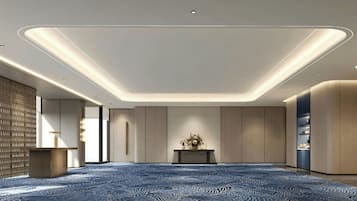 A spacious room with a patterned carpet, recessed ceiling lighting, and a central console table with a vase of flowers.