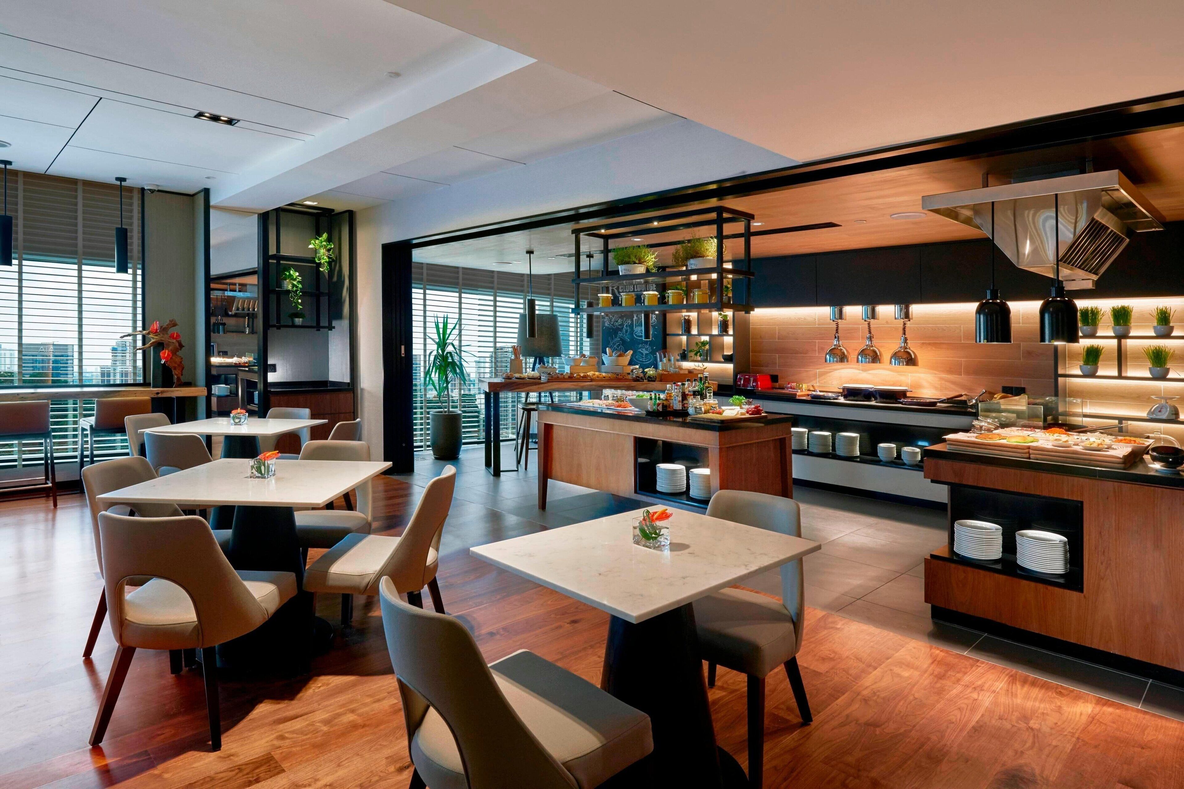 Un restaurante moderno con una isla central, zona de estar y cocina a la vista.