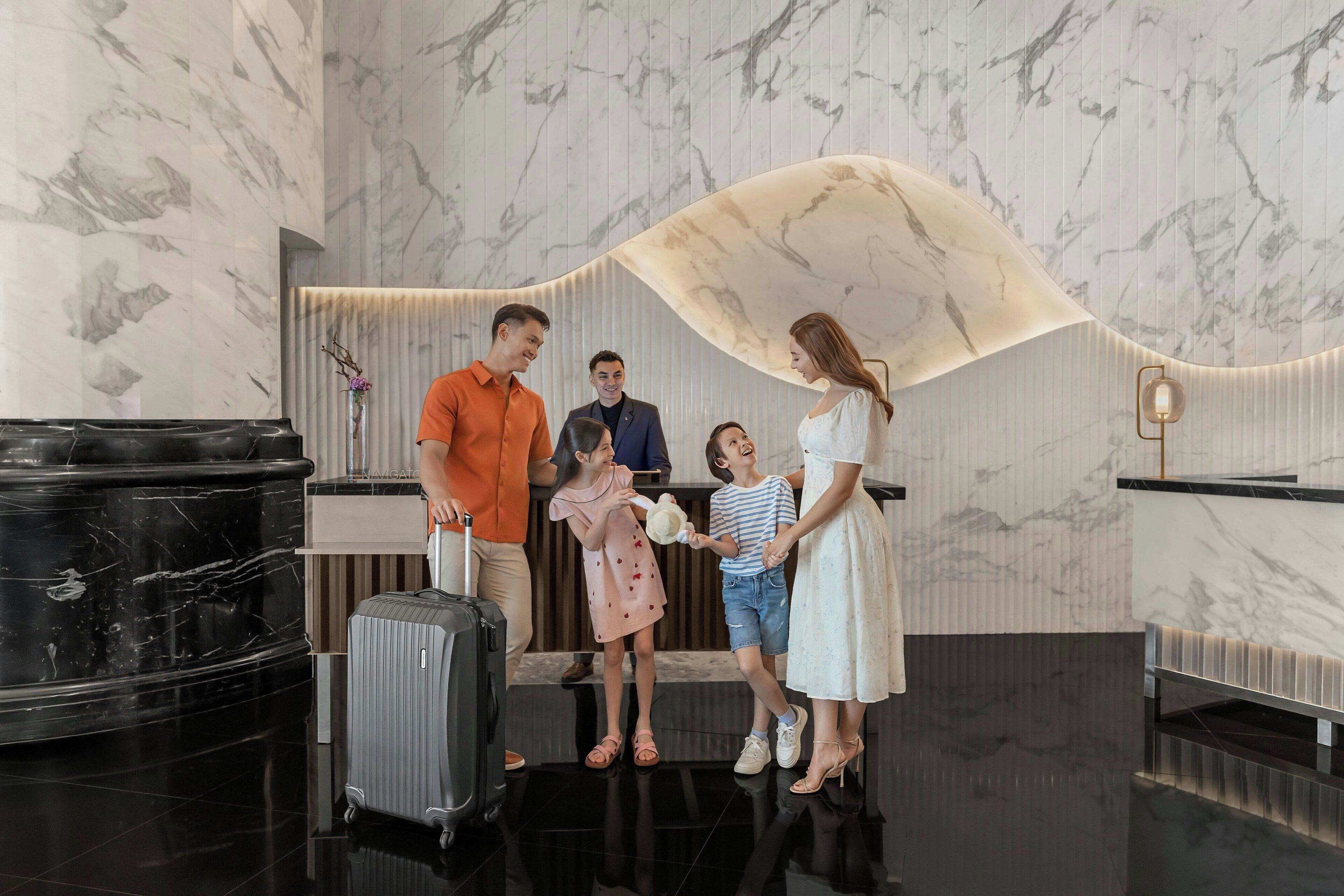 A hotel reception area with marble walls, a black reception desk, and a curved ceiling feature.