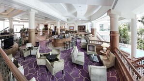 A spacious lobby with marble floors, a central bar area, and a staircase leading to a balcony with a pool view. - Dorsett Grand Labuan (Labuan)
