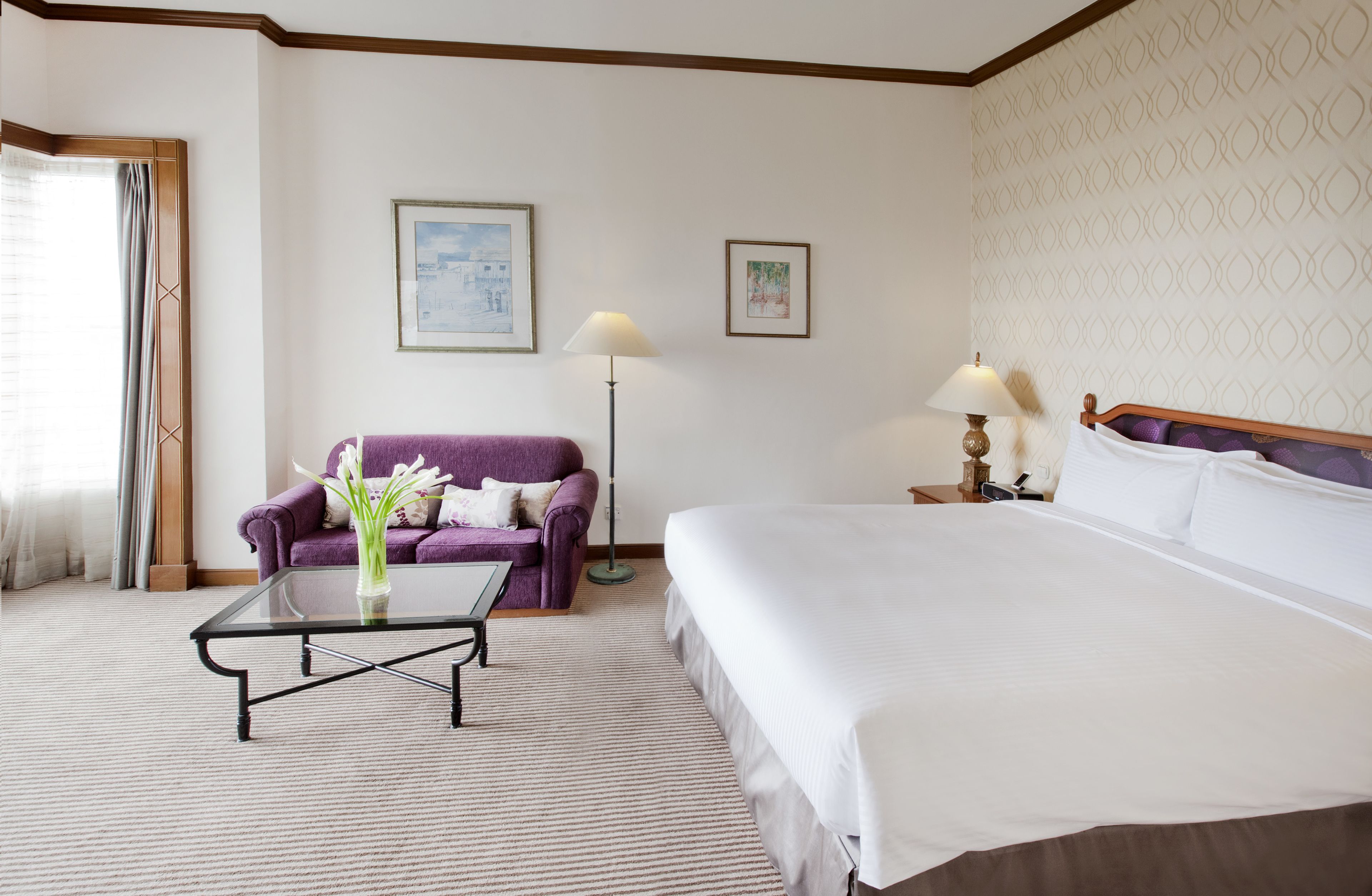 Una habitación de hotel con una cama grande, un sofá, una mesa de centro y dos lámparas.
