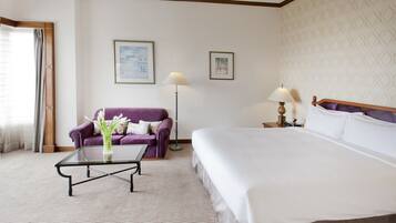 Una habitación de hotel con una cama grande, un sofá, una mesa de centro y dos lámparas.