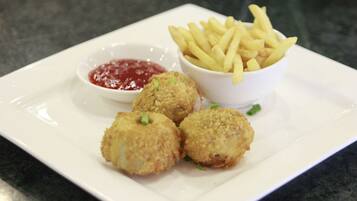 A plate with four breaded items, a bowl of fries, and a small bowl of ketchup.