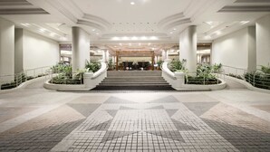 A spacious lobby with a central staircase, large columns, and potted plants. - Dorsett Grand Labuan (Labuan)