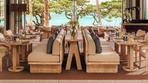 A spacious lounge area with a large wooden table, comfortable seating, and a view of the ocean. - One&Only Le Saint Géran (Belle Mare)