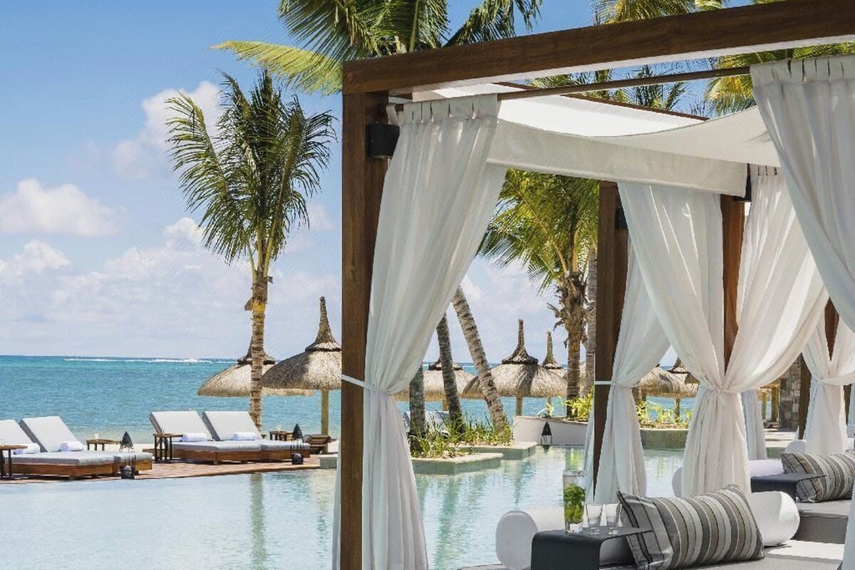 A poolside area with lounge chairs, a canopy, and a view of the ocean.
