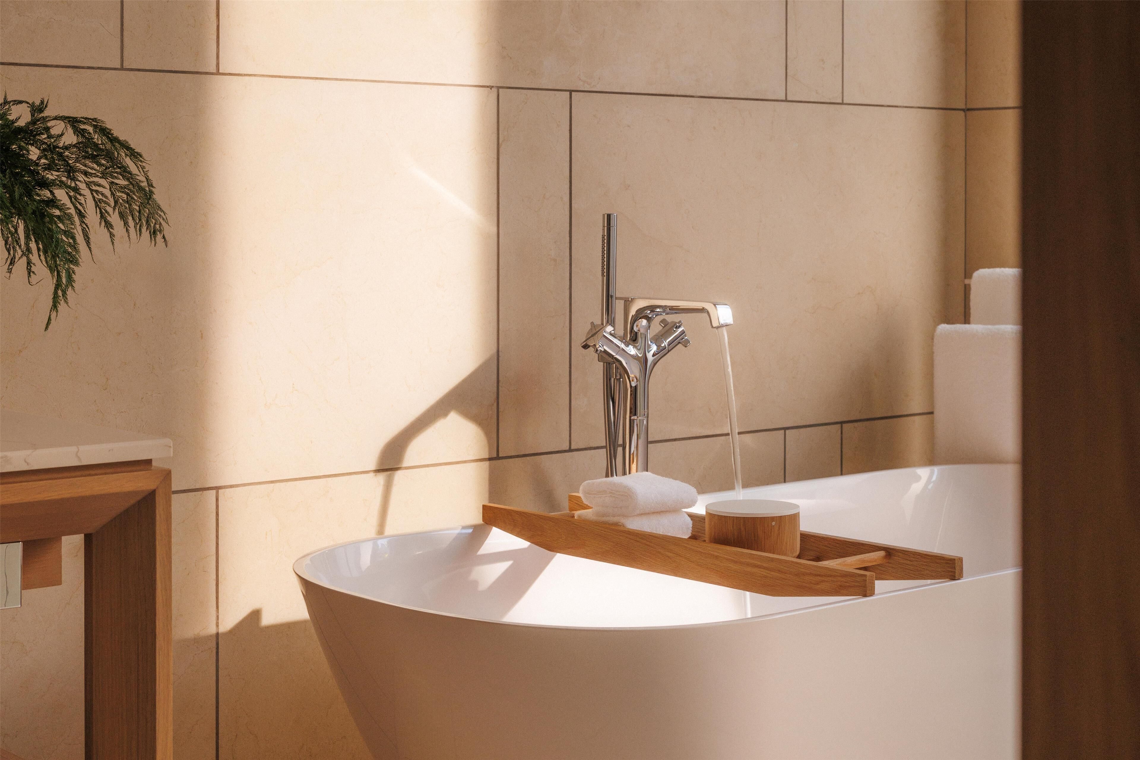 Un baño moderno con una bañera independiente, una bandeja de madera con una toalla y una planta a la izquierda.