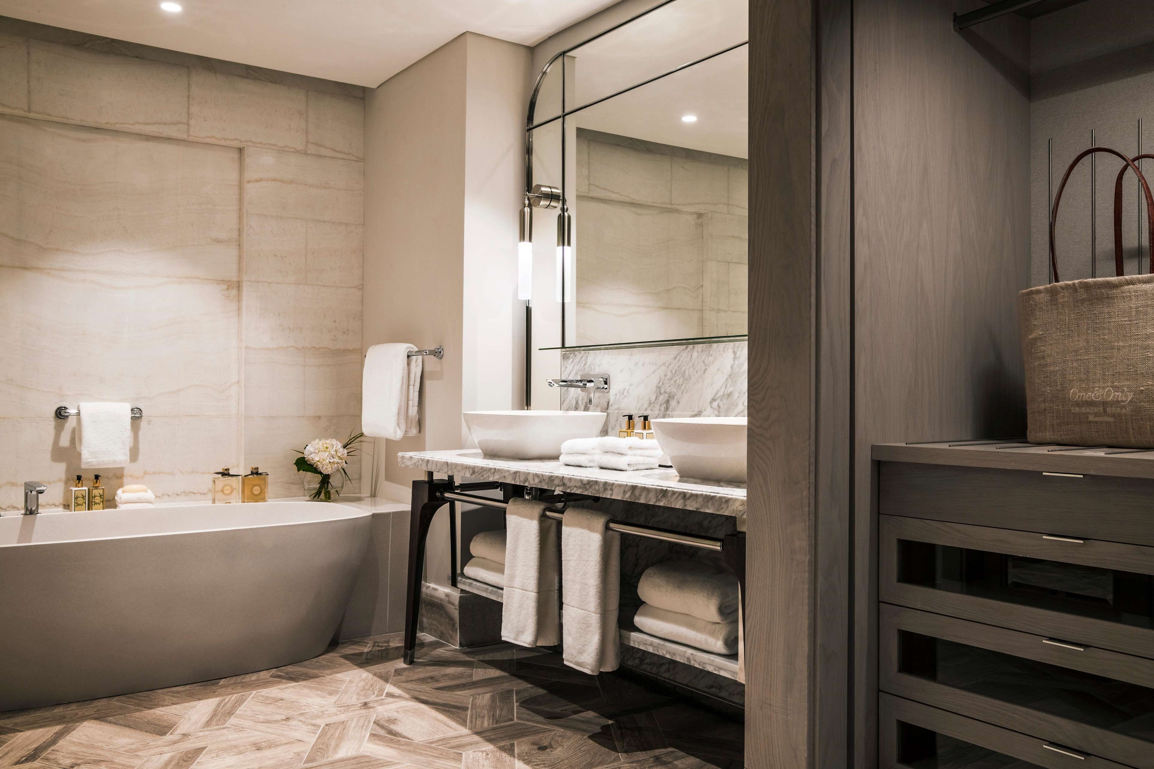 Un baño moderno con una bañera independiente, dos lavamanos y un espejo grande.