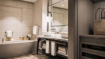 Un baño moderno con una bañera independiente, dos lavamanos y un espejo grande.