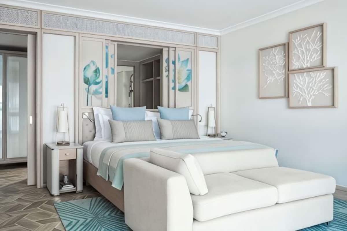 A bedroom with a bed, nightstands, a sofa, a mirror, and artwork on the wall.