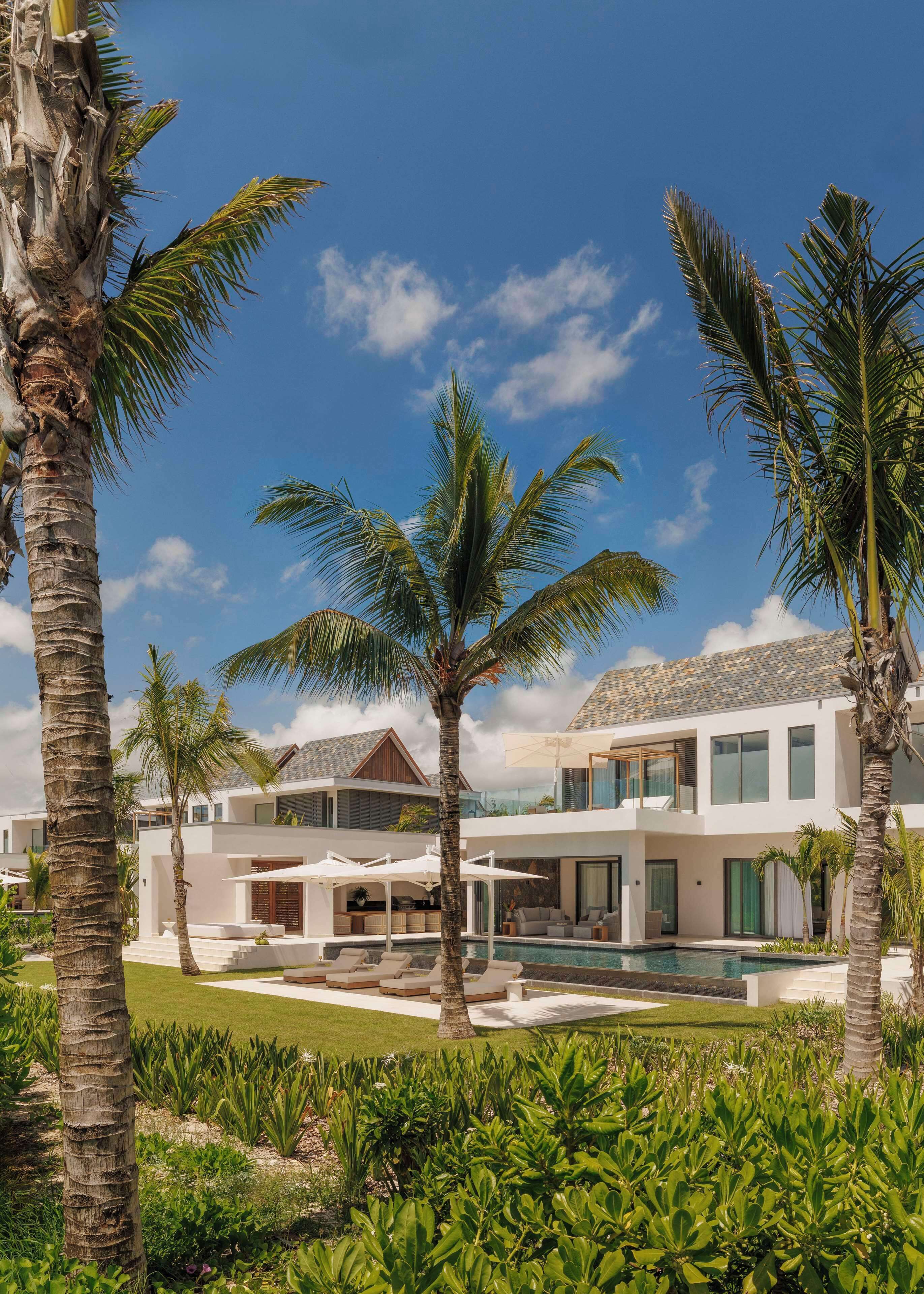 Ein modernes Resort mit Pool, Palmen und blauem Himmel.