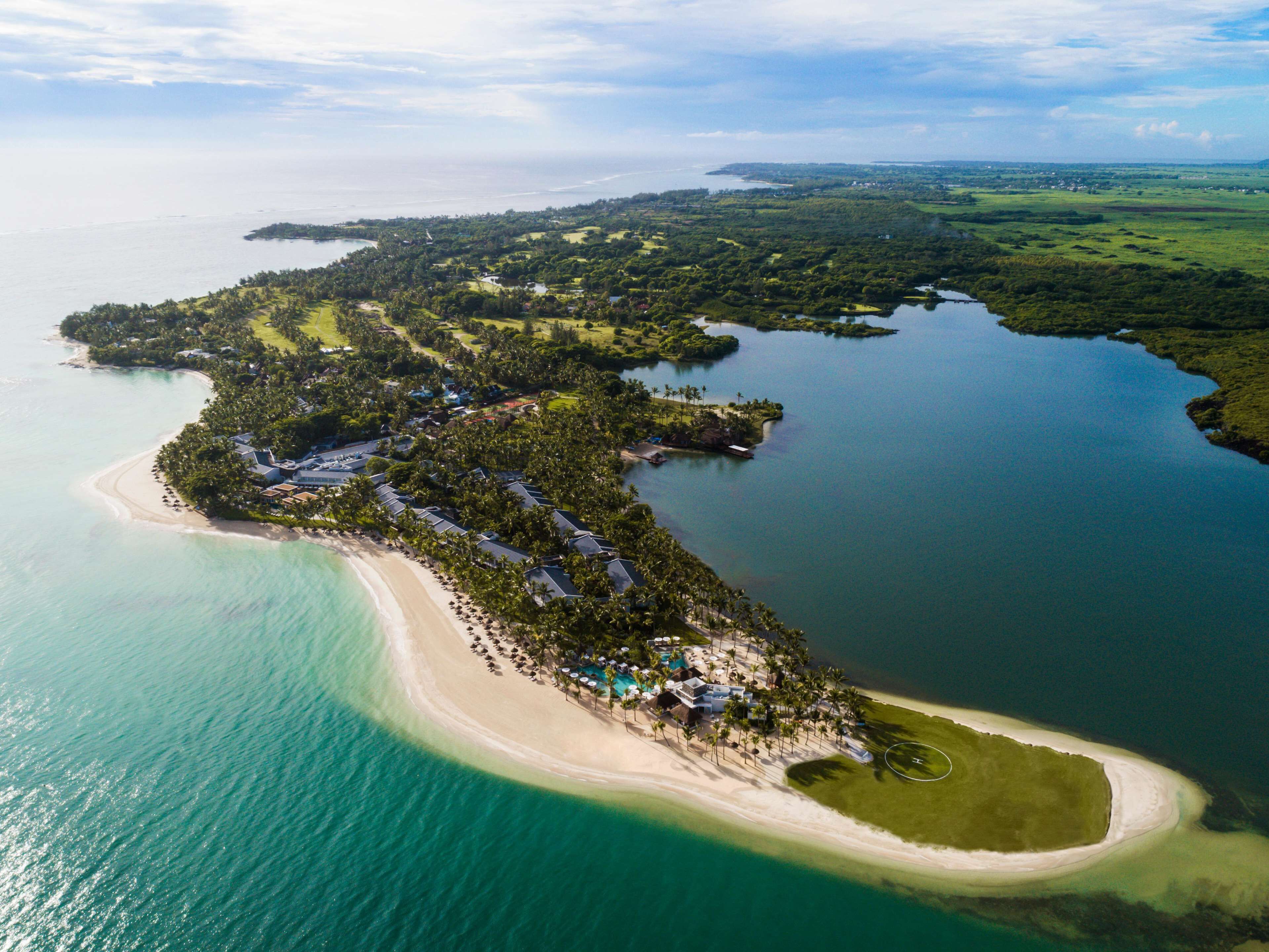 An aerial view of a coastal resort with a beach, water, and greenery.