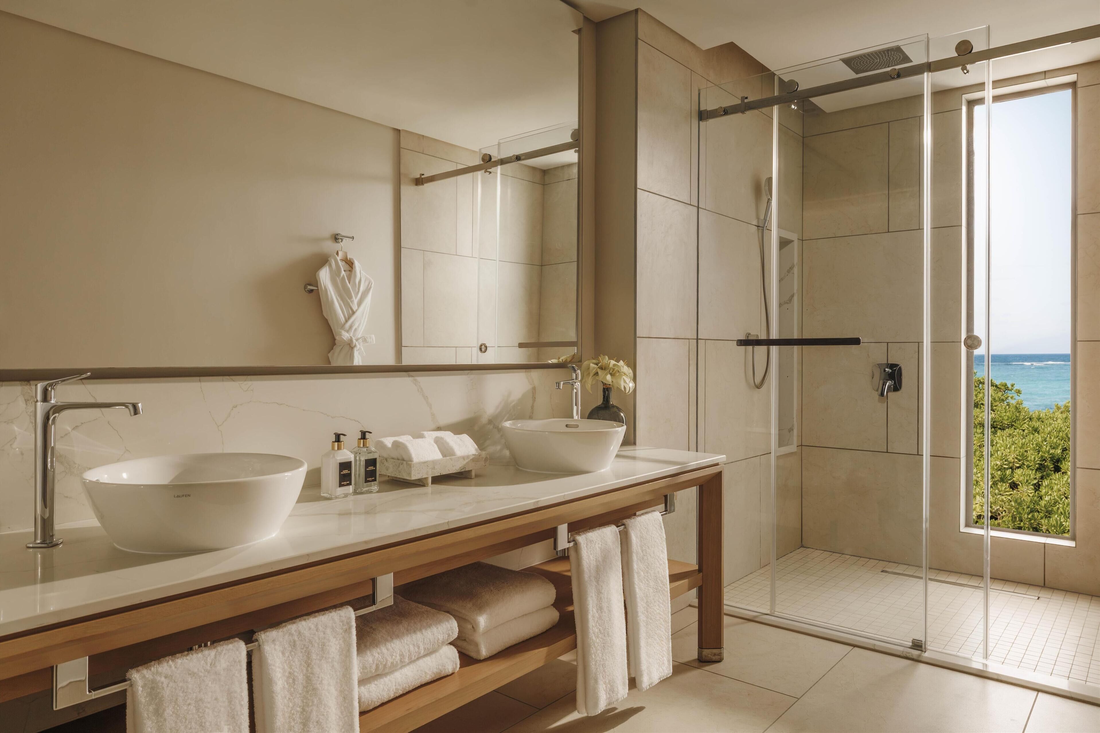 Une salle de bain moderne avec deux lavabos, un grand miroir et une douche à l’italienne.