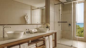 Un baño moderno con dos lavamanos, un espejo grande y una ducha con mampara de vidrio.