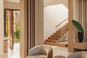 A modern interior with a wooden staircase, a seating area, and a view of the outdoors.