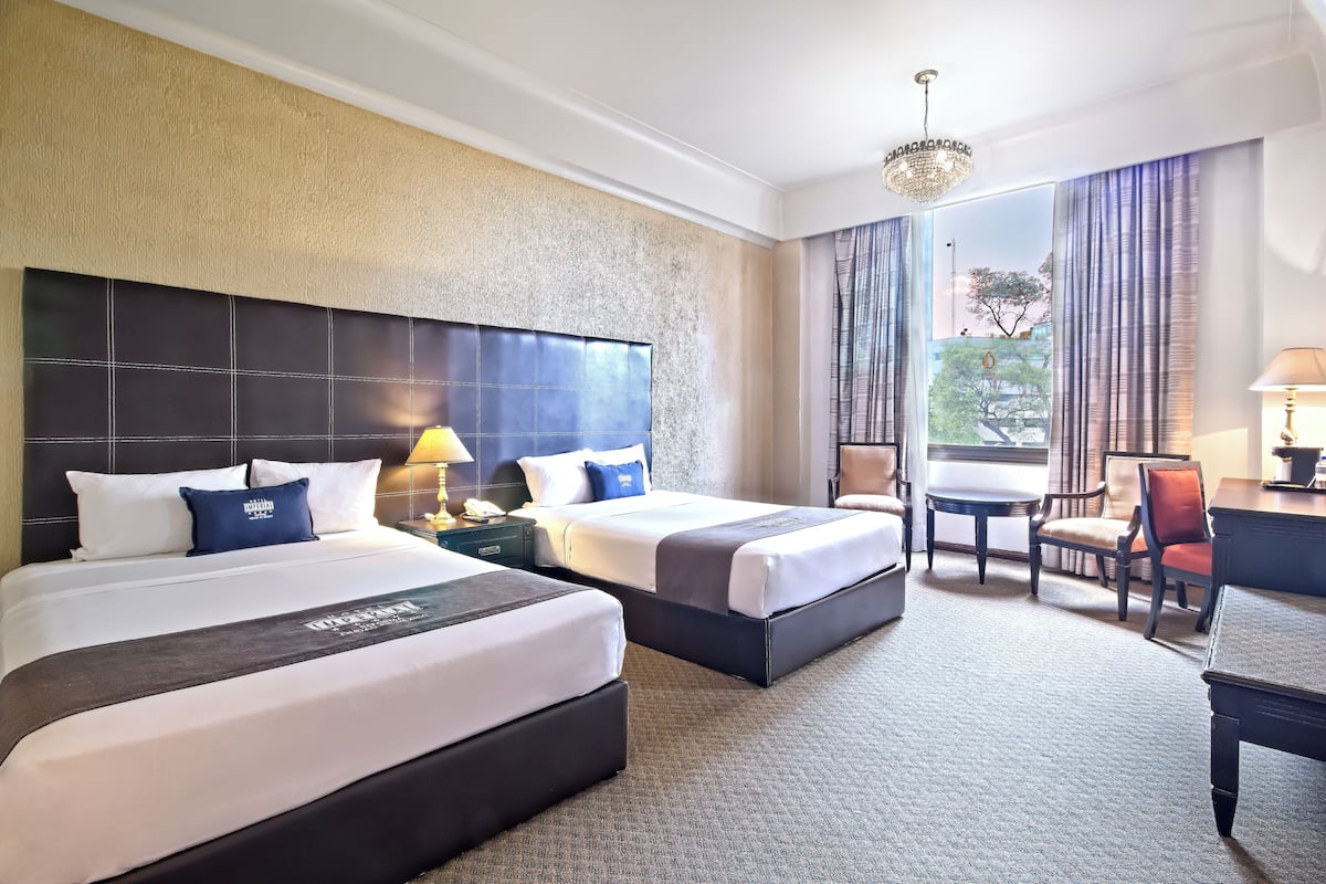Habitación de hotel con dos camas, un escritorio y una silla.