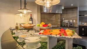 A buffet setup with various food items and beverages, including fruits, cheeses, and a bottle of wine, in a modern kitchen setting. - Hotel Imperial Reforma (Mexico City)