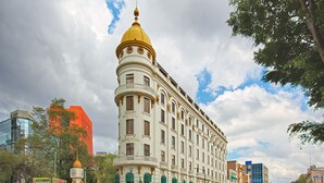 A historic hotel with a prominent golden dome, classic architecture, and a street view with modern buildings. - Hotel Imperial Reforma (Mexico City)