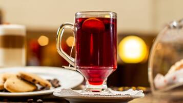 Una taza de vidrio transparente con asa, llena de una bebida roja, sobre un platito.
