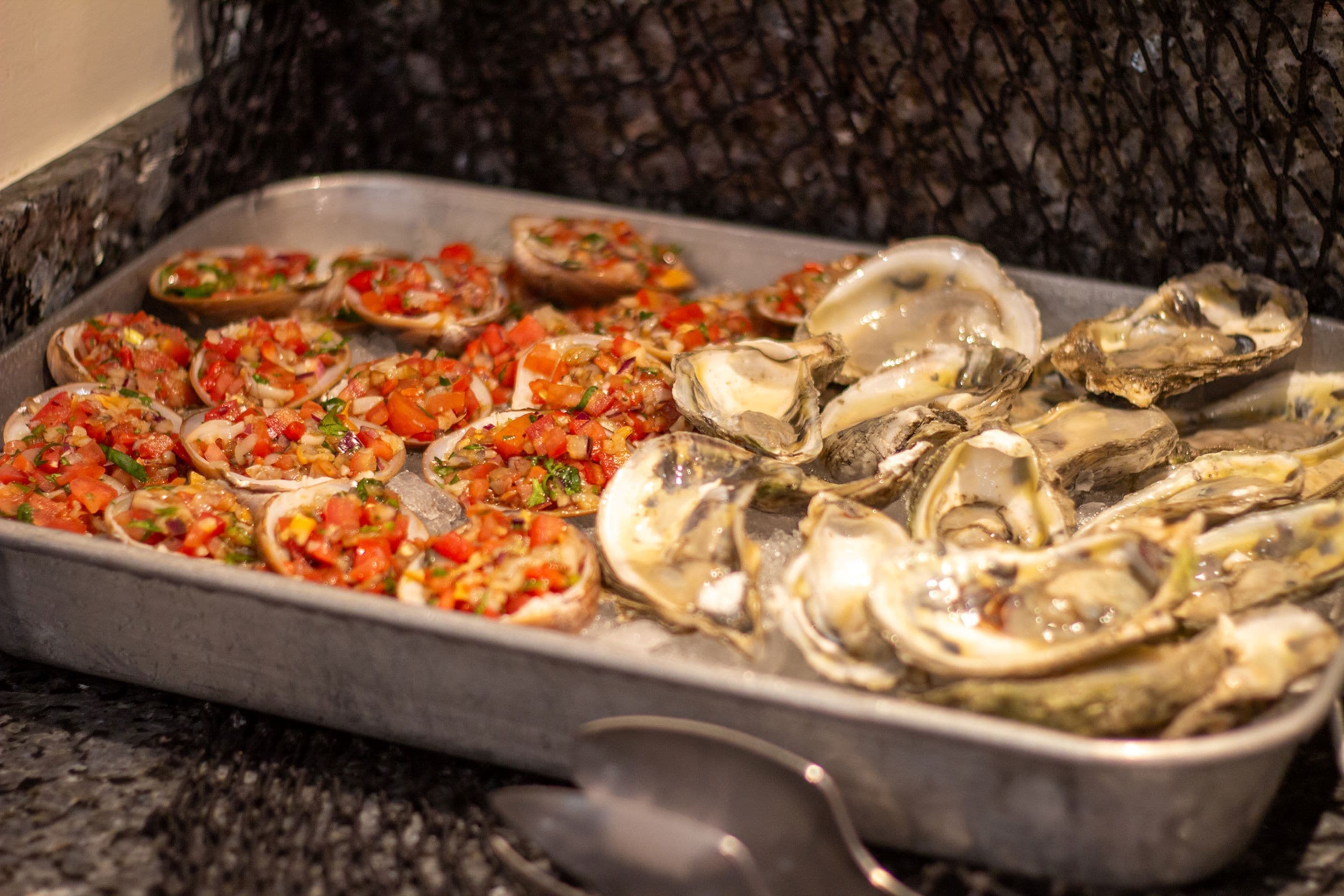 A tray of oysters with a tomato-based topping.