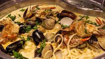 Prato de massa de frutos do mar com amêijoas, mexilhões e caranguejo, decorado com salsa.