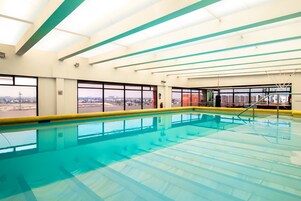 Une piscine intérieure offrant une vue dégagée sur la ville grâce à de grandes fenêtres.
