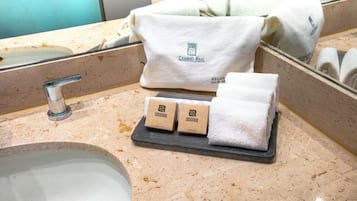 A bathroom with a sink, a towel, and two small boxes on a tray.
