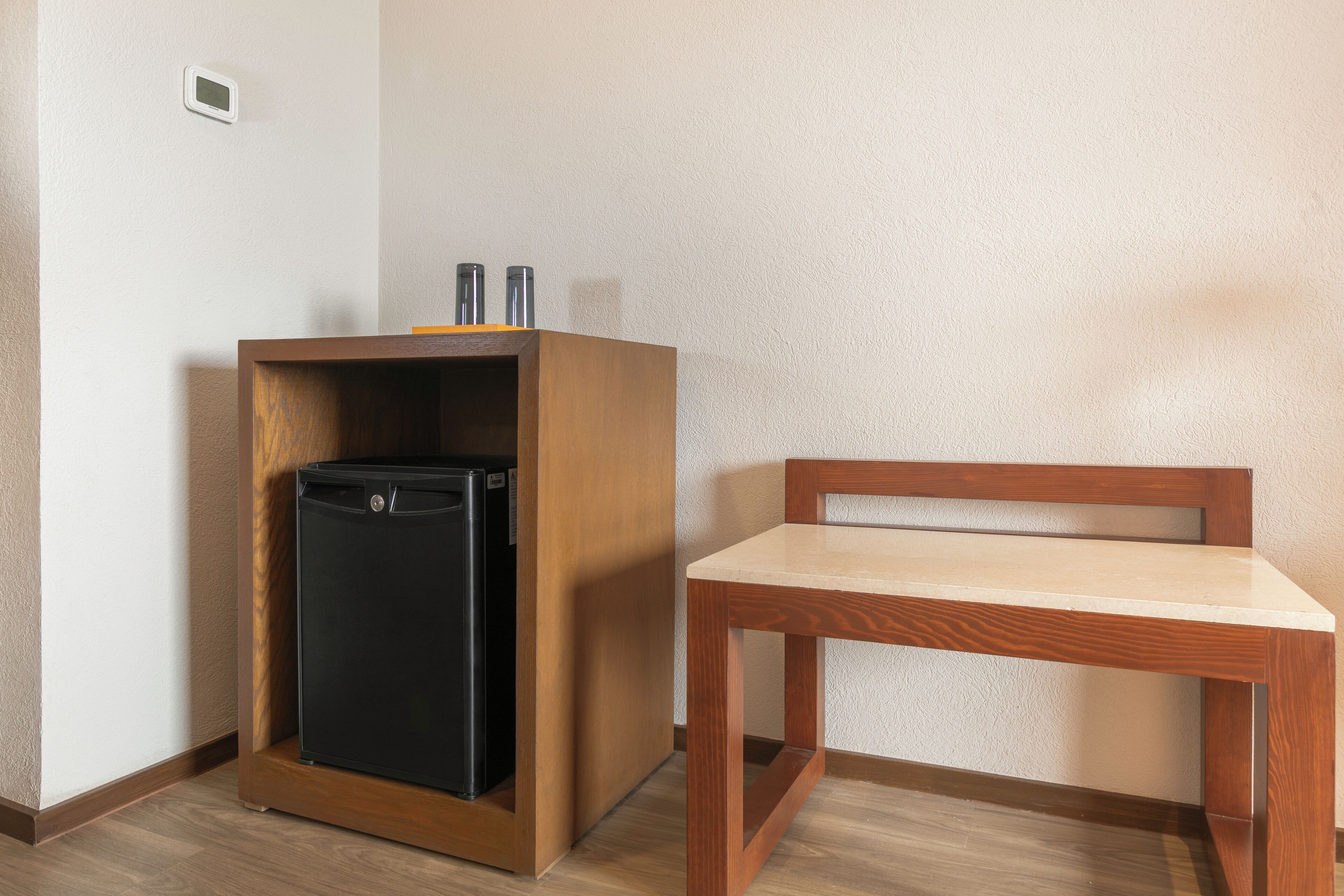 A compact room with a wooden cabinet containing a black appliance, a wooden chair, and a small table.