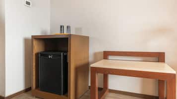 A compact room with a wooden cabinet containing a black appliance, a wooden chair, and a small table.