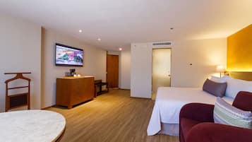 Ein Hotelzimmer mit Bett, Schreibtisch, Stuhl, Fernseher und Kleiderschrank.
