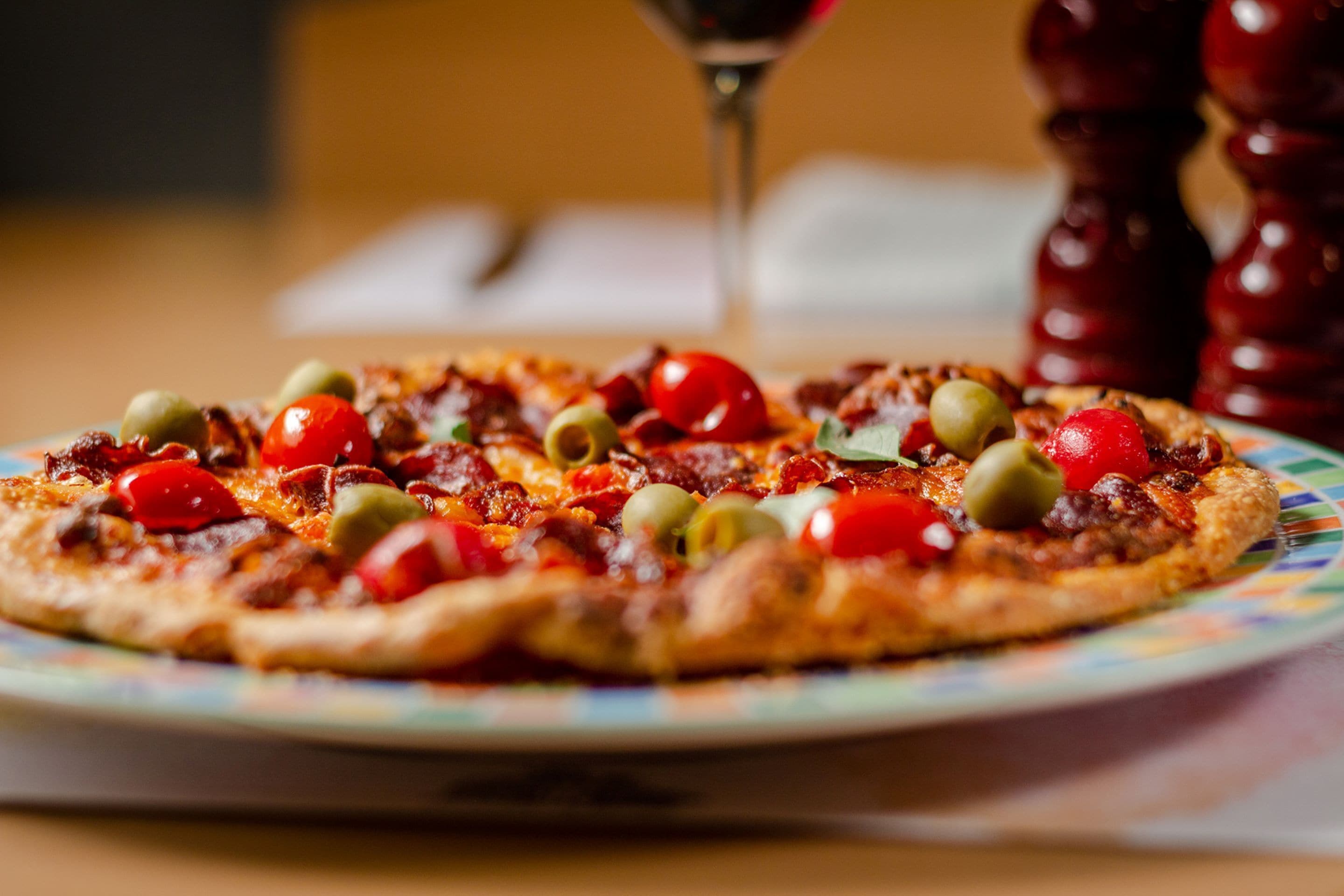 A pizza with various toppings on a colorful plate.
