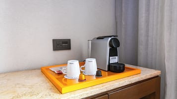 A coffee station with a coffee maker, two cups, and a tray on a countertop.