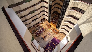 A multi-level atrium with a central open space featuring seating areas and a staircase. - Camino Real Aeropuerto Mexico (Mexico City)