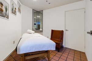 Un dormitorio con cama, una silla, un espejo y una puerta.